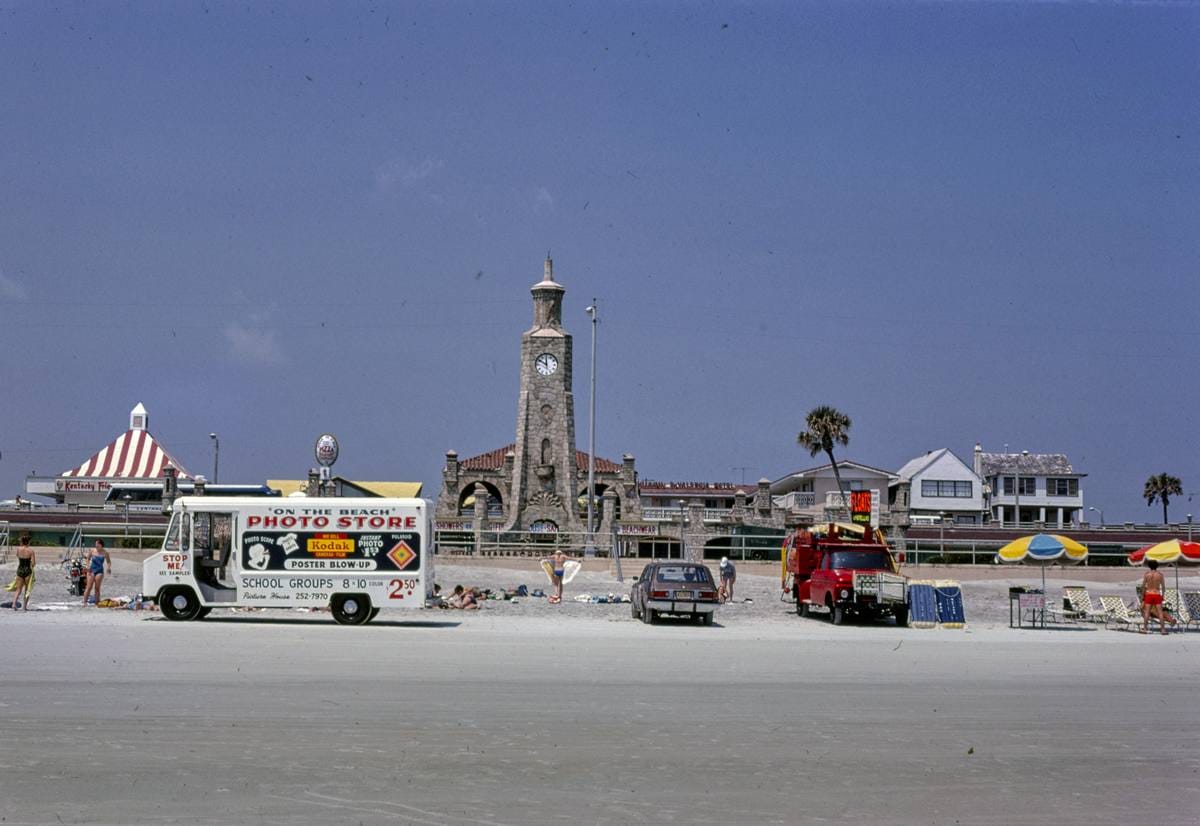 Historic Photo : 1979 [Photo store on the beach van and cars, with view of clock tower], Daytona Beach, Florida | Photo by: John Margolies |
