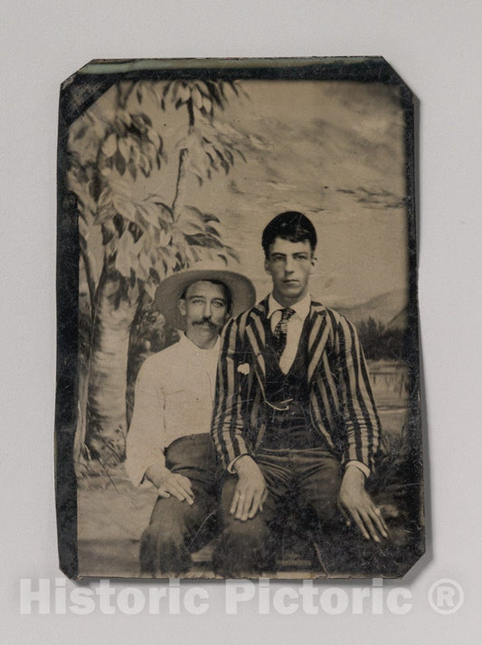 Art Print : Young Man in a Striped Jacket, Sitting on The Lap of Another Man in Front of Painted Outdoor Backdrop - Artist Unknown : Vintage Wall Art