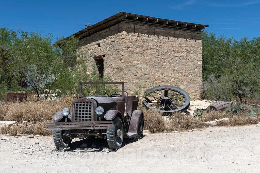 Photograph- An old jalopy outside an abandoned stone building in the"ghost town," some of which is still occupied and some of which consists of ruins of the Chisos quicksilver-mining company