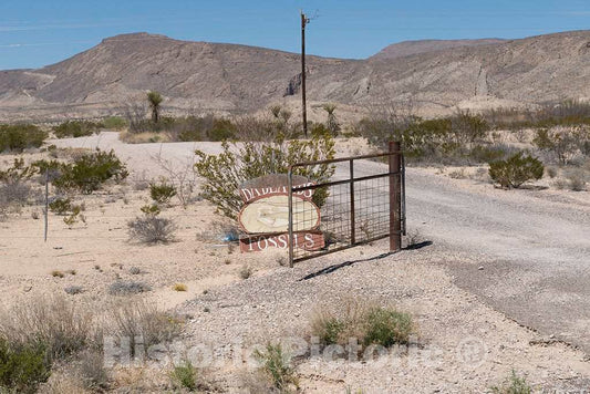 Photograph- Dilapidated sign and gate announcing"Badlands Fossils" stand along the road that connects Big Bend National Park with its state equivalent, Big Bend Ranch State Park, in southern