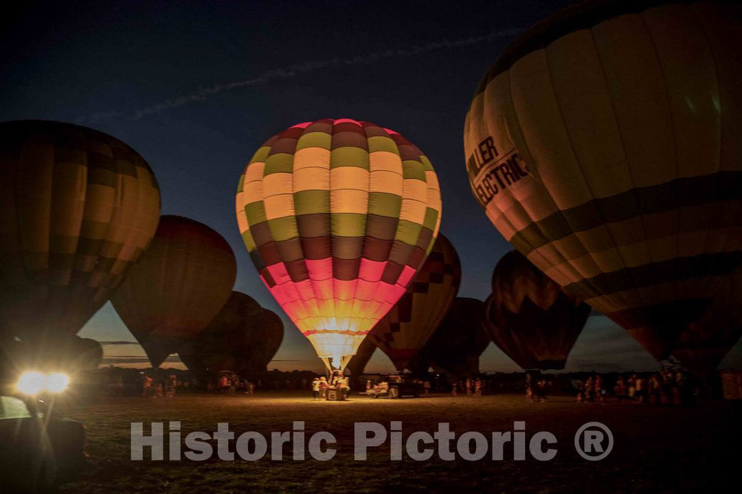 Colorful balloons delight the assembled crowd with a night glow as pilots fire the burners on the ground at the National Balloon Classic,  1