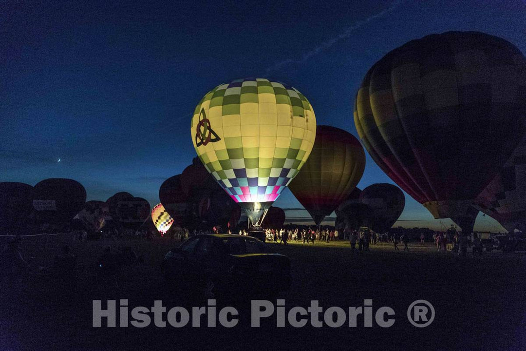 Colorful balloons delight the assembled crowd with a night glow as pilots fire the burners on the ground at the National Balloon Classic,  3