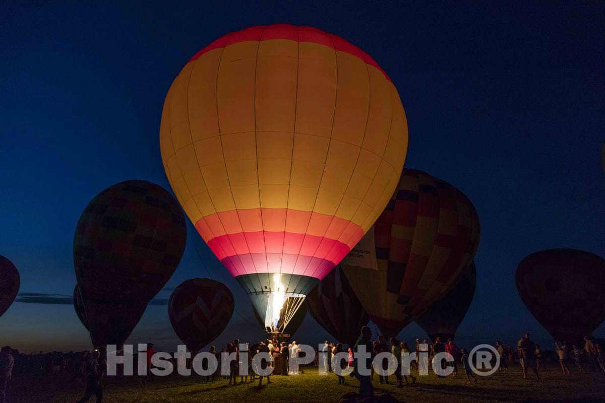 Colorful balloons delight the assembled crowd with a night glow as pilots fire the burners on the ground at the National Balloon Classic,  6
