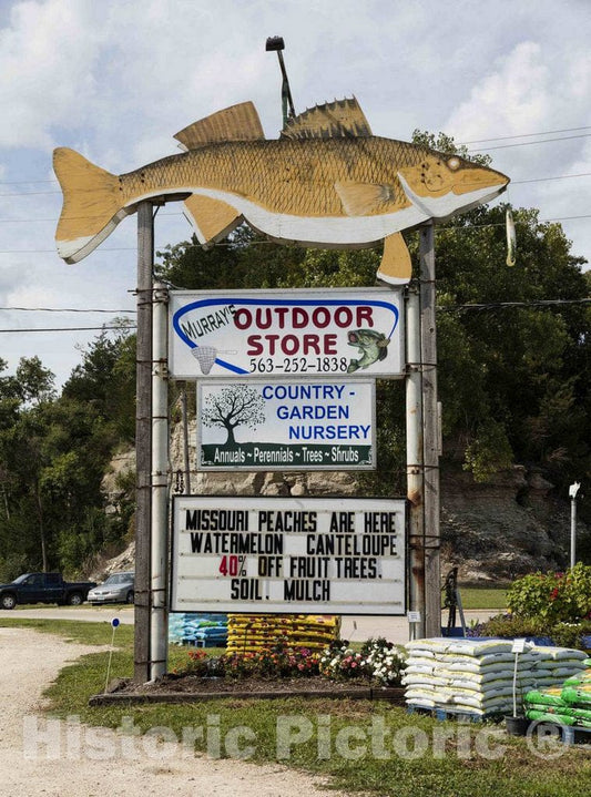 Photo - This Store in Guttenberg, Iowa, Offers Many Goods, Food, and Services for Sale. But The Figure at The top of its Store Sign Makes its Specialty Clear