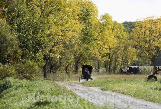 Photo- Horse-drawn Amish buggies journey down a country road at Yoder's Amish Home, an authentic Amish farm that began accepting visitors in 1983 near Walnut Creek in central Ohio